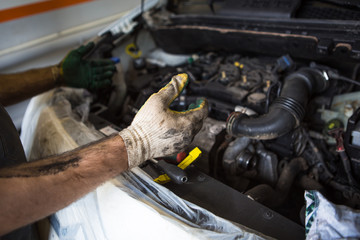 Mechanic with a tool in his hands repairing the motor of the machine. The process of working in the service station