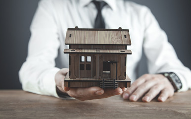Real estate agent holding wooden house.