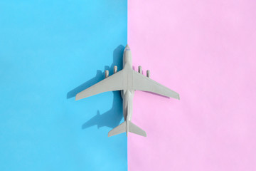 Miniature plane on blue and pink background in minimal design. Travel holiday concep. Flat lay, top view, copy space