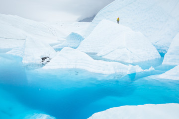 Man on a large ice fin surrounded by glacial pool on the Matanuska Glacier in Alaska