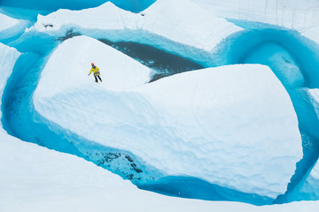 Walking a narrow ridge on an island of ice in a large blue lake in Alaska.