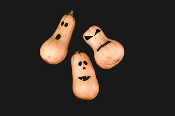 Funny scary face Halloween pumpkins on black background. Flat lay, top view background.
