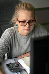 The girl in glasses sitting  under paper work in the office