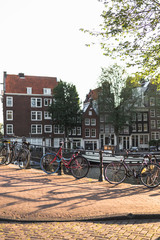 Obraz premium Bicycles parked along a bridge on the central streets of Amsterdam in sunset light.