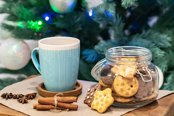 Winter theme. Christmas tea with spices, cup of tea with cinnamon, anise, cookies in a shape of star on wooden background linen napkin. Mug of tea with Christmas decoration. Copy space for text