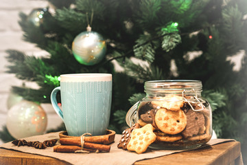 Winter theme. Christmas tea with spices, cup of tea with cinnamon, anise, cookies in a shape of star on wooden background linen napkin. Mug of tea with Christmas decoration. Copy space for text
