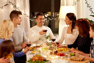 celebration, holidays and people concept - happy family having dinner party, drinking red wine and toasting at home
