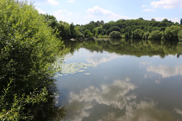 Fototapeta na wymiar Clouds are reflected in the river. Sunny windless weather. Peace and silence. Natural beauty.
