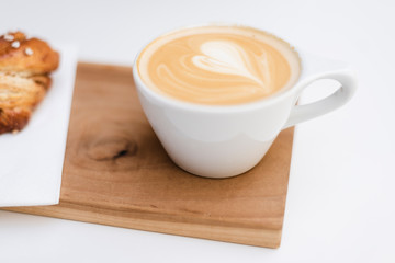 A cup of cappuccino on wooden board.