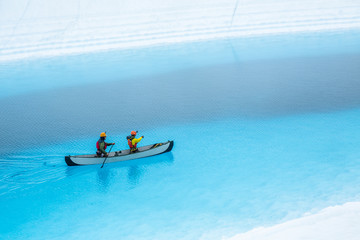 Two men paddling a canoe across a glacial lake in Alaska. Blue pool on top of a glacier in the...