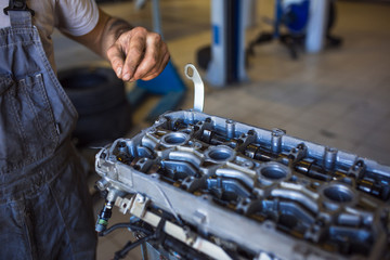 Mechanic with a tool in his hands repairing the motor of the machine. The process of working in the service station