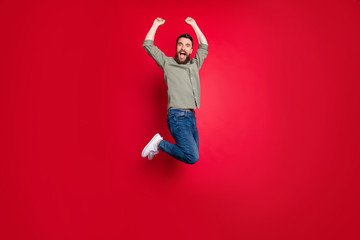 Full length body size photo of rejoicing happy man jumping with victory while isolated with red...