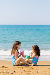 little girls sit sit opposite each other and drink from colored beautiful cocktail glasses Family vacation concept