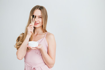 Girl holding a useful bamboo toothbrush and a jar of tooth powder
