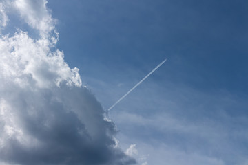 Bright blue sky with backlit cloud and an airplane shooting thru it