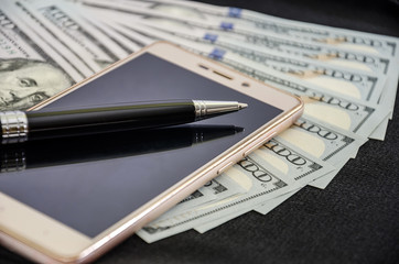 smartphone with pen on dollars. Close-up.