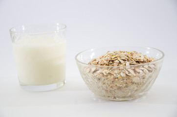glass of milk and dry oatmeal isolated on white background