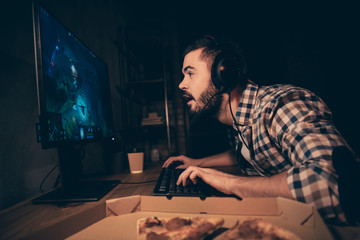 Close up side profile view photo he him his guy videogame headset microphone teammates concentrated look screen expect breakthrough victory win wear casual plaid checkered shirt cafe table indoors