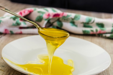 a spoonful of sweet, fresh honey. Honey in a spoon on a white plate background. Close-up.