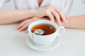 Young beautiful girl brews tea in a useful reusable metal strainer