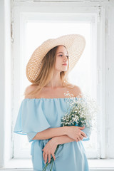 Girl with long hair and hat posing with a bouquet of white flowers