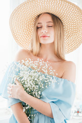 Girl with long hair and hat posing with a bouquet of white flowers