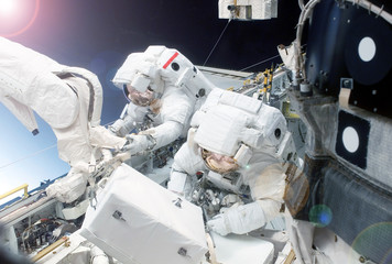 Two astronauts are engaged in experiences and repair at the space station, in an outer space. ...