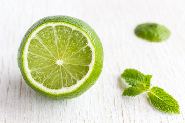 Healthy food concept: cut top lemon and a sprig of mint on white background close up..