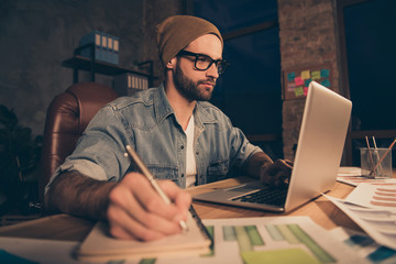 Photo of attentive guy work at dark time making notes of online lesson wear casual outfit sit modern office