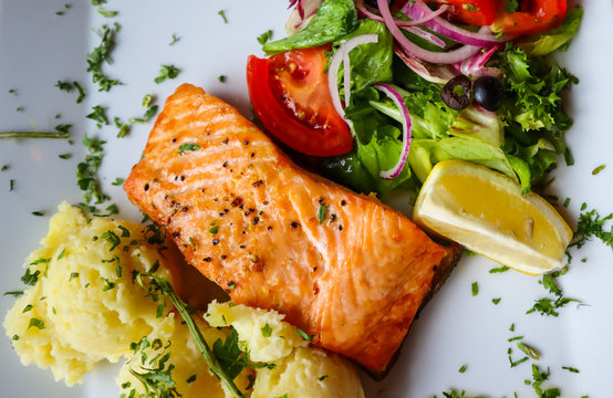 Baked Salmon With Mash Potato, Lemon, Tomatoes, Red Onions, Olives And Salad Leaves On White Background