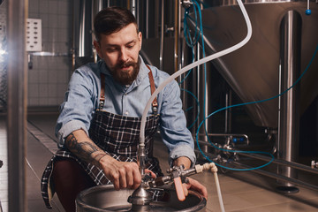 Bartender adds more beer from the tap into the smaller vat.
