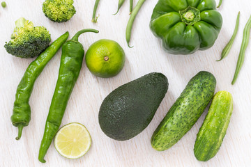 A set of green vegetables: asparagus, pepper, broccoli, avocado on a white background. Top view