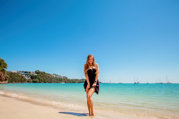 Fototapeta na wymiar Beautiful young woman with long hair in a black dress standing near the sea and relax on the beach on Phuket, Thailand