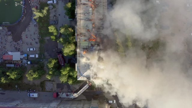 Burning roof of a residential high-rise building, clouds of smoke from the fire. firefighters extinguish the fire. top view