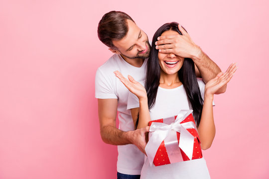 Photo of cute nice couple of fallen in love liking to gift each other red package with bow while isolated with pink background