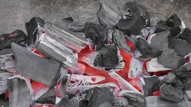 Charbon de bois br&ucirc;lant doucement dans un barbecue en pierre