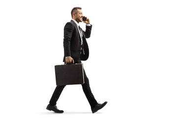 Businessman walking and talking on a mobile phone - Powered by Adobe