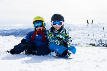 Fototapeta na wymiar Two young children, siblings brothers, skiing in Austrian mountains on a sunny day