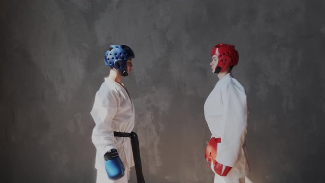 Young boxers are preparing for sparing, standing in a fighting position. Confident mixed race guys training before battle. They take martial pose. Kimono, helmet, gloves, indoor.