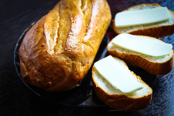 Fresh white bread with a Golden crust and three pieces of loaf with melted cheese in a glass plate