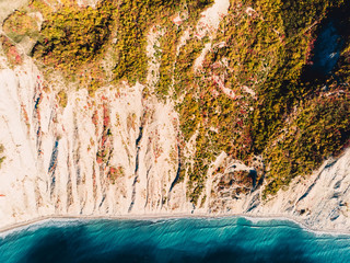 Aerial view of rocky sea shore with cliff and blue sea. Autumnal time