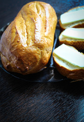 Fresh white bread with a Golden crust and three sandwiches with melted cheese in a glass plate