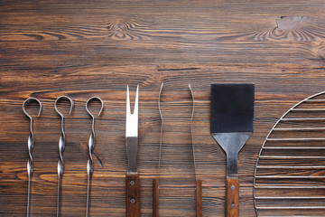 Row of barbecue utensils on wooden table
