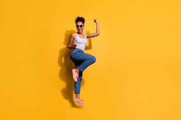 Fototapeta na wymiar Full length side profile body size photo beautiful she her dark skin lady jumping high yell yeah triumphant champion wear casual jeans denim pants trousers tank-top isolated bright yellow background