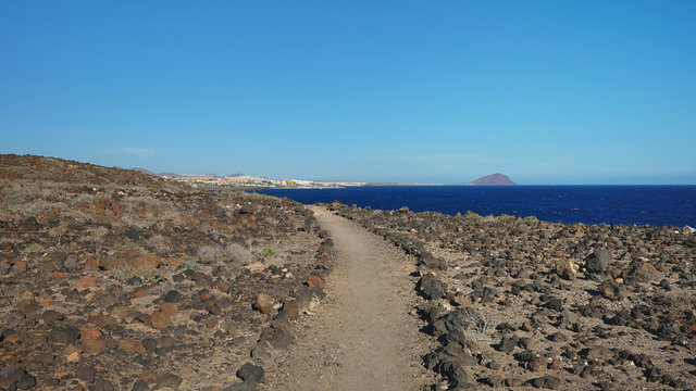 Hiking trail nearby Atlantic through the arid volcanic landscape of the island, views from Montana Amarilla towards Marina San Miguel, outdoor natural attraction in Tenerife, Canary Islands, Spain
