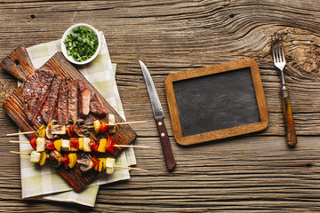 Overhead view of grilled steak and meat skewer with blank slate