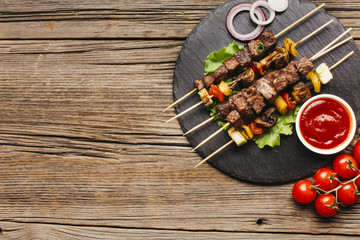 Barbecue skewers with meat and vegetable on circular black slate