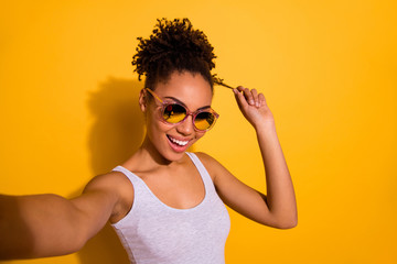 Close up photo beautiful nice pretty she her dark skin lady summer weekend rest relax make take selfies blogger play fingers wind curl wear sun specs casual tank-top isolated bright yellow background