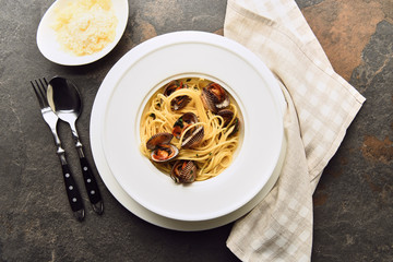 top view of delicious pasta with mollusks served with grated cheese and napkin