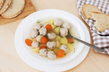 Soup with meatballs and vegetables on the table top view. Bowl of soup with meat. Healthy eating.